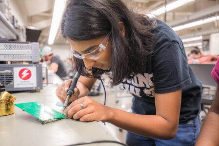 Student technician in FEDC soldering a circuit board.
